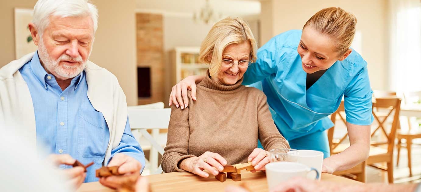 nurse with senior residents working on wooden puzzle